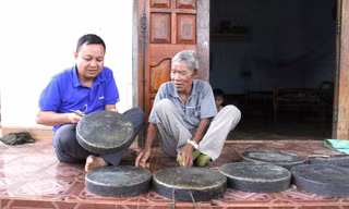 Nghệ nhân Y Krai Cil (phải) giới thiệu về bộ chiêng quý của gia đình 