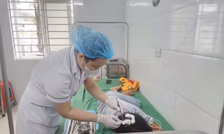 Bé H.T.N.L đang được bác sĩ thay băng vết thương do bị cha dượng bạo hành. Ảnh: HOÀI NAM