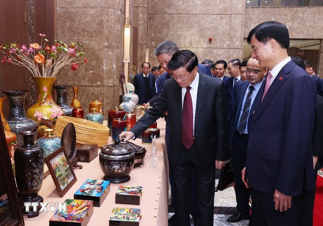 Tổng Bí thư, Chủ tịch nước Lào Thongluon Sinsoulith tham quan không gian trưng bày các sản phẩm thủ công mỹ nghệ làng nghề truyền thống của Hà Nội. (Ảnh: Văn Điệp/TTXVN)