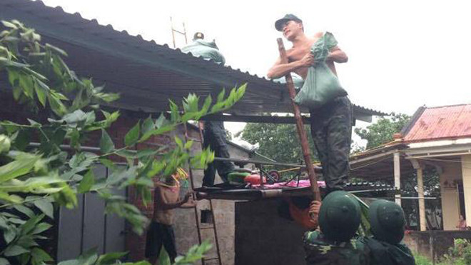 Chèn mái nhà trong gió bão ở thị trấn Cửa Tùng. ẢNH: H.TÁO-H.T-N.DO