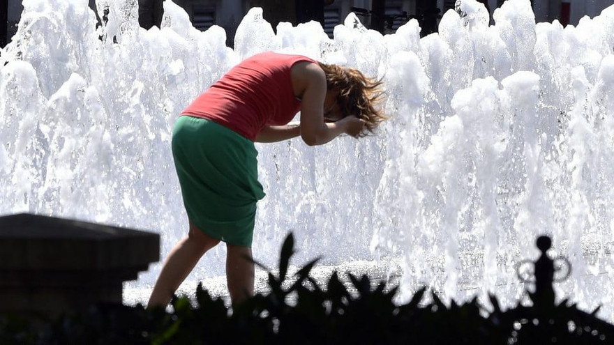 Một người phụ nữ lấy nước ở đài phun nước để hạ nhiệt