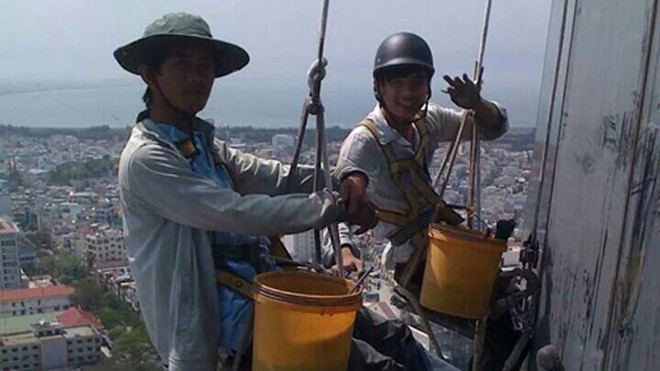 Những người thợ lau kính phải cheo leo giữa không trung để mưu sinh - Ảnh: Bảo Nguyên 