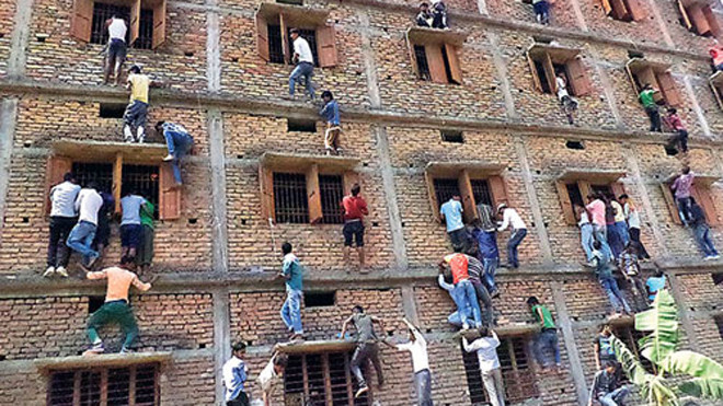 Phụ huynh và người thân thí sinh bất chấp nguy hiểm để leo lên tầng cao ném tài liệu cho con em tại một điểm thi ở quận Vaishali, bang Bihar. Ảnh: Hindustan Times.
