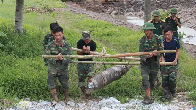 Lính công binh di dời quả bom khỏi khu vực sản xuất của người dân. Ảnh: T.L.