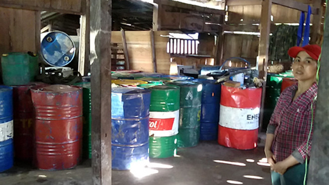 Kiểm tra nhà kho của Thảo, cảnh sát phát hiện hàng chục thùng phuy và can nhựa đựng xăng dầu mua từ các tài xế. Ảnh. Hữu Long.