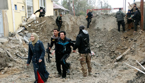 Lực lượng an ninh Iraq và các chiến binh người Sunni giúp những người dân bị mắc kẹt thoát khỏi khu vực nằm dưới sự kiểm soát của IS ở Ramadi hôm 4/1. Ảnh: AP