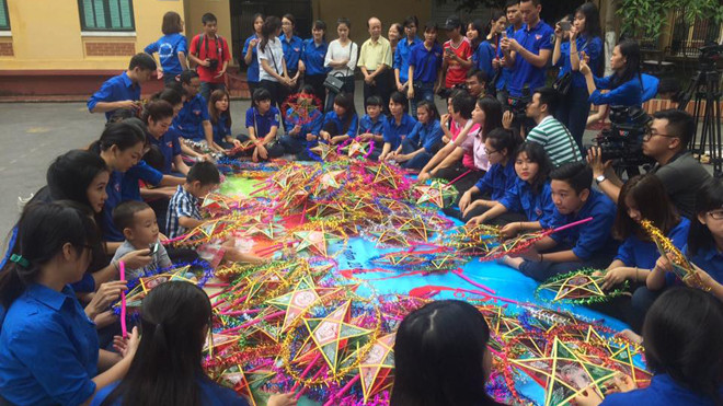 Các bệnh nhi được các tình nguyện viên hướng dẫn làm đèn trung thu tại sân bệnh viện