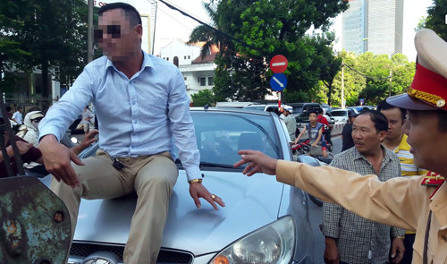 Nam tài xế cố thủ trên nóc xe khi cảnh sát đưa xe cẩu đến. Ảnh: Sơn Dương