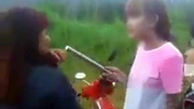 Hình ảnh cắt từ clip trên mạng xã hội Facebook cho thấy thiếu nữ nhuộm tóc vàng dùng gậy sắt đánh vào đầu bạn.