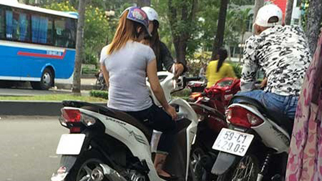 Hai cô gái bán dâm dừng xe cạnh một thanh niên làm nhiệm vụ canh chừng. Ảnh: HT.