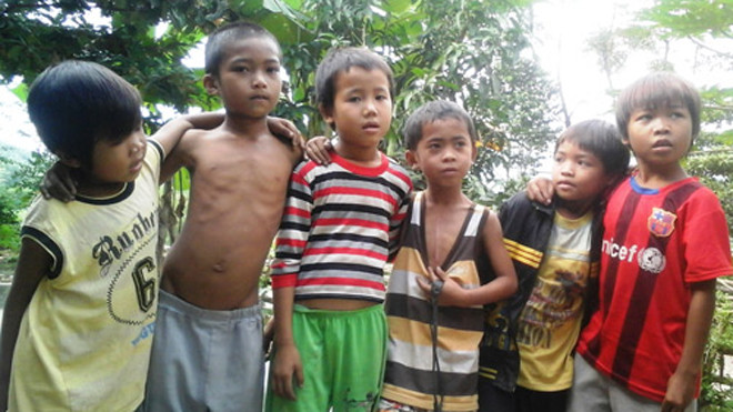 Cậu bé Hồ Kiểng (9 tuổi, thứ ba từ phải sang) chỉ vào ngực mình cho biết đó là vết mổ tim mới được thực hiện cách đây vài tháng. Theo cán bộ xã Hương Liên thì bố mẹ Kiểng là anh em họ hàng. Ảnh: Đức Hùng