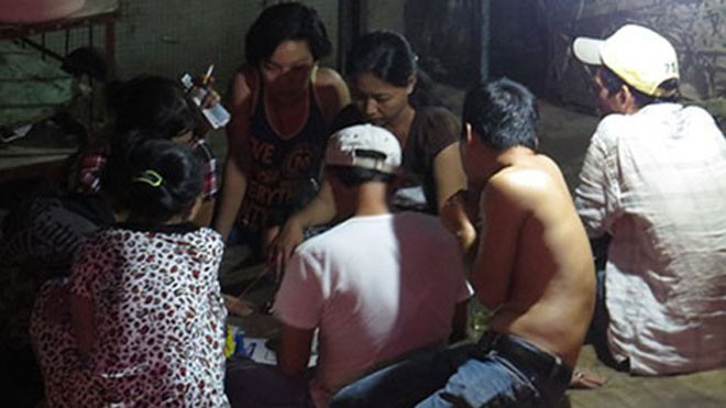 Sạp chợ biến thành sòng cá ngựa., có cả nam lẫn nữ. Ảnh chụp đêm 12/12.