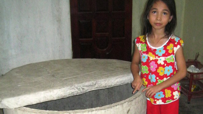 Cháu Thủy bên giếng nước mà cháu bị rơi xuống. 