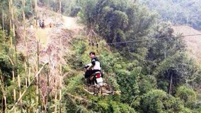 Cả người và xe đang đu ở độ cao hàng chục mét . Ảnh: FB Laocaionline.com. 