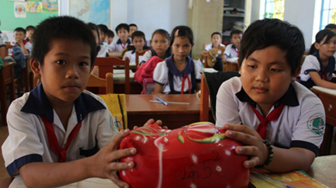 Các em học sinh lớp 5/2, Trường tiểu học Vĩnh Hòa (Ba Tri, Bến Tre) nuôi heo đất giúp các bạn nghèo trong lớp. 