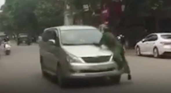 Lái xe bất chấp trên nắm ca pô có người vẫn nổ máy bỏ chạy - Ảnh: Cắt từ clip