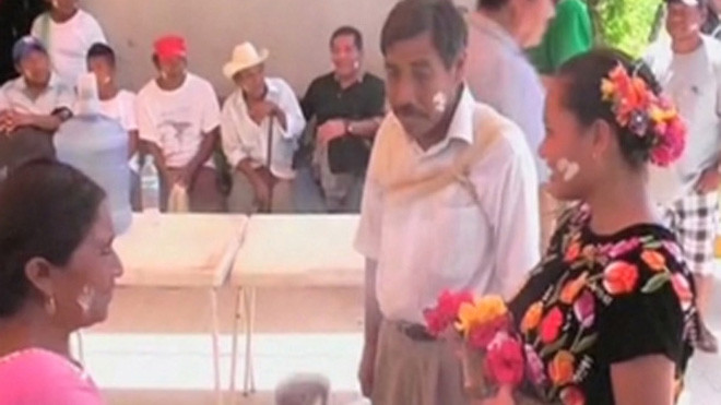 "Cô dâu cá sấu" được một người phụ nữ bế trong khi cử hành hôn lễ. 