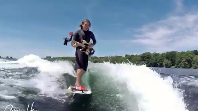 Chàng trai vừa lướt ván, vừa chơi đàn guitar