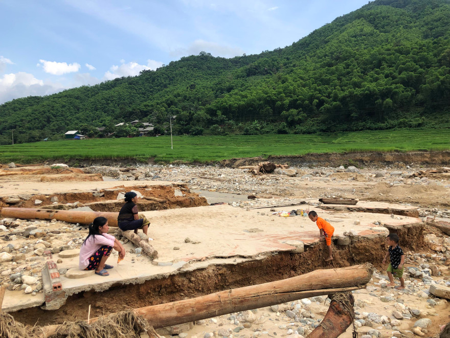 Cụ Nít cùng người thân ngồi bên nền nhà cũ bị lũ cuốn trôi, gọi tên các con đang mất tích. Ảnh: Hoàng Lam