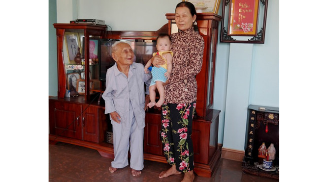 Cụ Một bên cạnh con dâu và chắt nội. Cụ có hơn 40 cháu, chắt. Ảnh: Đoàn Nguyên.