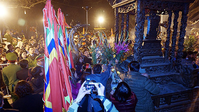 Người đi lễ lao vào cướp hoa, lộc mặc ban tổ chức đang thu dọn đồ lễ. Ảnh: Giang Huy.