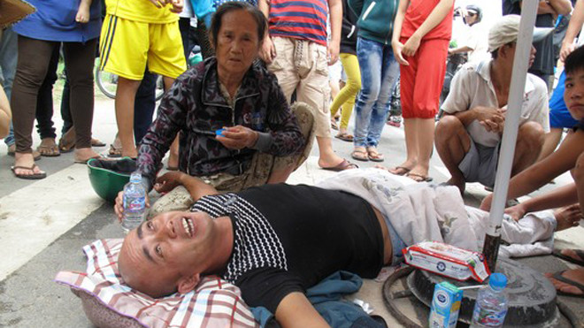 Ông Trương Văn Dũng, vừa lăn lộn dưới đường vừa luôn miệng quát tháo, nói nhảm.