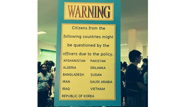 Du khách xếp hàng sau một tấm bảng ở cửa khẩu Arayaprathet. Tấm bảng ghi du khách Việt Nam nằm trong số ít những đối tượng khách có thể bị tra hỏi bởi nhân viên hải quan - Ảnh: V.L.P 