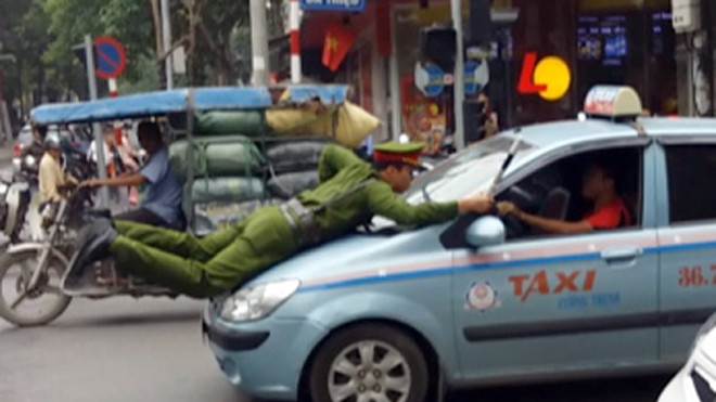 Cảnh sát trẻ phải nhảy lên nóc capo và bám vào cần gạt nước khi tài xế cho xe đi tiếp. Ảnh: Bá Đô