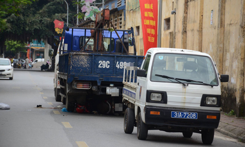 Hiện trường vụ tai nạn, chiếc xe máy của nạn nhân nằm trong gầm chiếc xe tải chạy lùi (màu xanh)