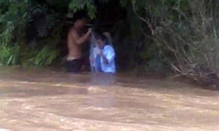 Hình ảnh cô giáo chuẩn bị chui vào túi nilon để người dân đưa qua suối trong những ngày lũ. Ảnh cắt từ clip báo Tuổi Trẻ