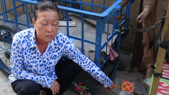 Bị phát hiện, người đàn bà ném tiền vào gầm xe ba gác. Ảnh: Long Hồ/VnExpress