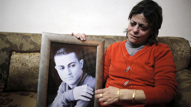 Mẹ của Muhammad Musallam, người Israel Arab bị Nhà nước Hồi giáo ở Syria bắt với cáo buộc là gián điệp, khóc khi ôm ảnh con trai. Ảnh: Reuters.