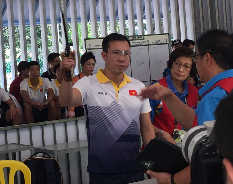 Xạ thủ Hoàng Xuân Vinh khá căng thẳng ngay từ lúc các trọng tài kiểm tra súng trước bài bắn chung kết 50m súng ngắn hơi ảnh HUY HOÀNG