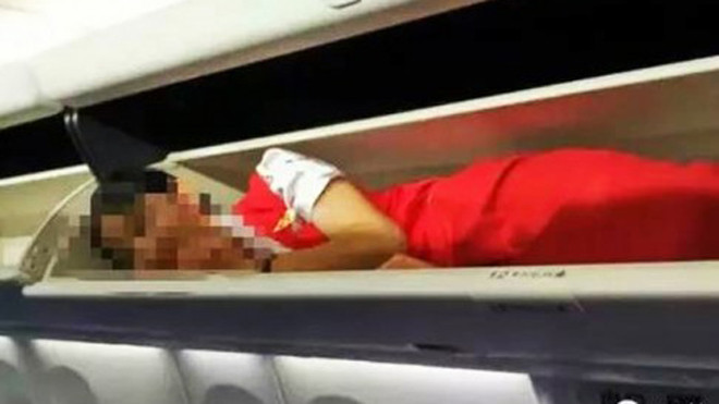 Một tiếp viên nằm trên hộc hành lý (Ảnh: Sina)