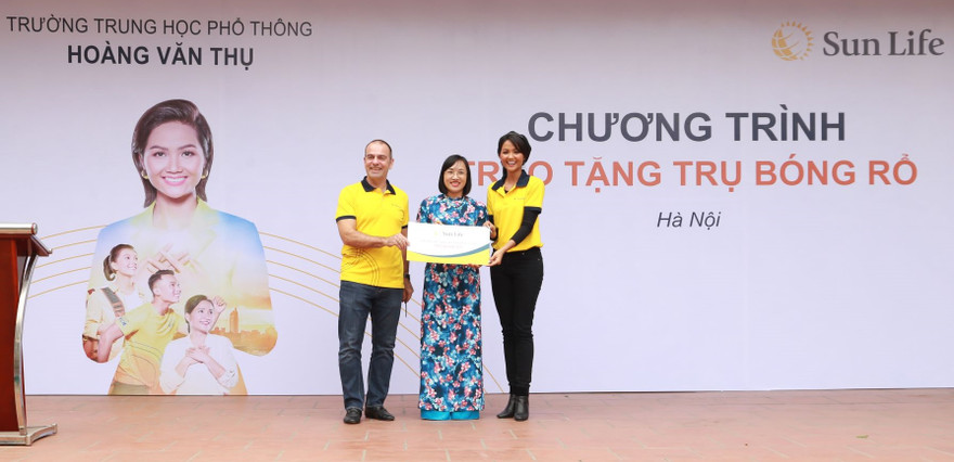 Ông Larry Madge - Tổng Giám đốc Sun Life Việt Nam và Hoa hậu H'Hen Niê trao biểu trưng trụ bóng rổ cho trường Trung học phổ thông Hoàng Văn Thụ, Hà Nội.