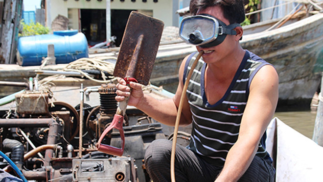 Út Nghĩa kiểm tra đồ nghề trước khi trao cho bạn lặn. Ảnh: Phúc Hưng