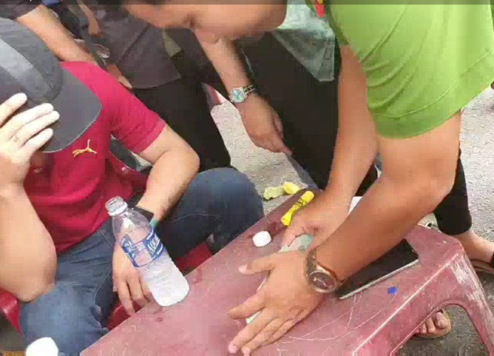 Đối tượng (áo đỏ) bị đưa về trụ sở công an