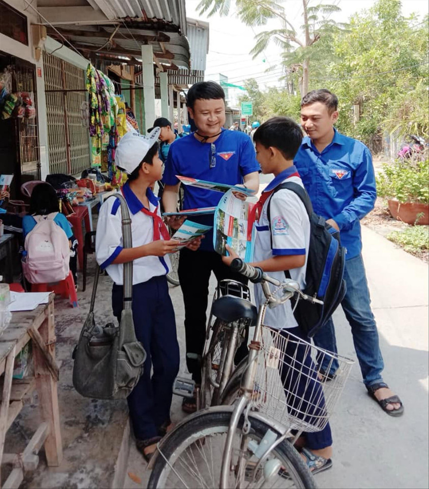 Anh Trần Quốc Bủ, Bí thư Đoàn xã Đất Mới (thứ hai, từ trái sang) phát tờ rơi phòng chống đuối nước cho các em học sinh 