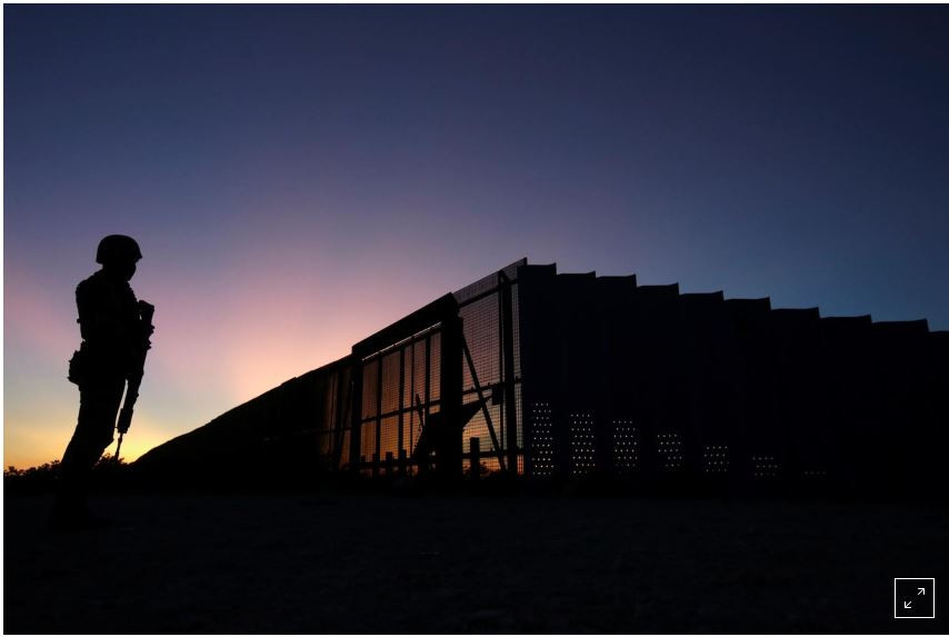 Một binh sỹ thuộc lực lượng Vệ binh quốc gia Mỹ đứng gác ở khu vực biên giới Mỹ-Mexico, phía trước là hàng rào chắn bằng thép. Ảnh: Reuters 