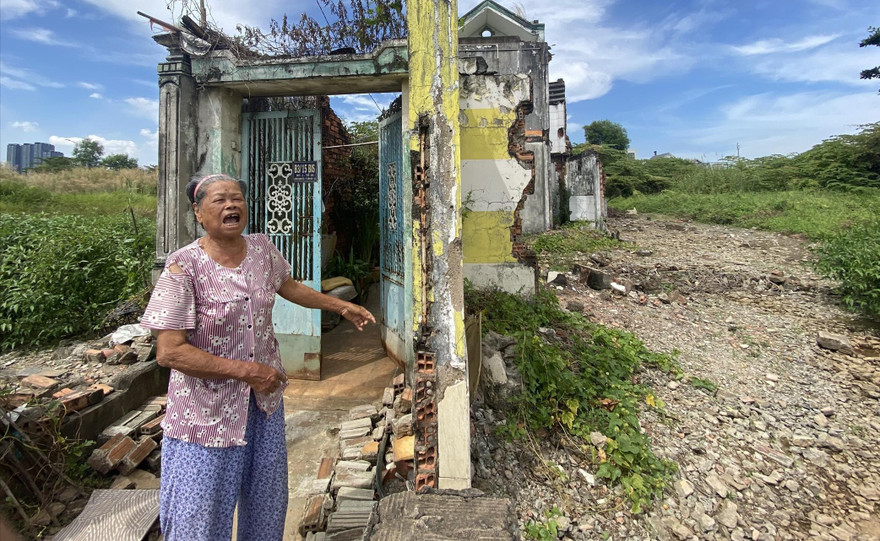 Bà Nguyễn Thị Giáp (80 tuổi) bên căn nhà bị đập loang lổ và lau sậy cao lút đầu người ở Thủ Thiêm 