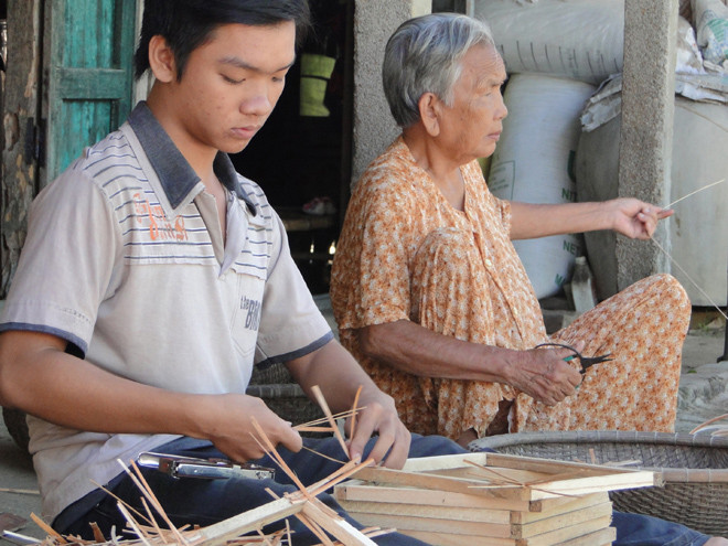 Hình ảnh em Nguyễn Thanh Nhân (8 năm trước) cùng ngoại đan lát tre mây kiếm tiền ăn học đăng trên báo Tiền Phong. Ảnh: Nguyễn Thành 