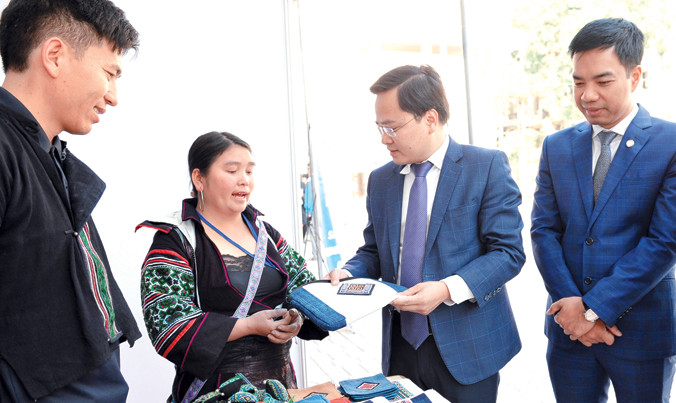 Chị Thào Thị Sùng giới thiệu sản phẩm thổ cẩm của CLB với Bí thư T.Ư Đoàn Nguyễn Anh Tuấn. Ảnh: Xuân Tùng.