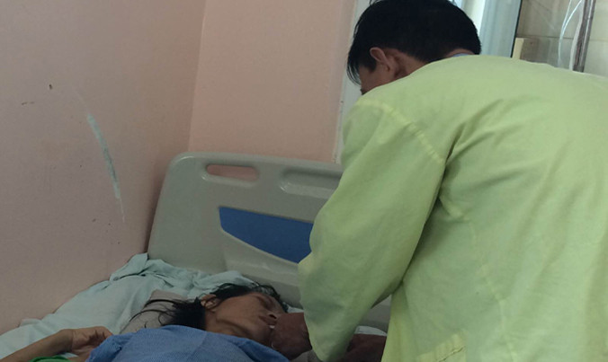 Bệnh nhân H. đang được anh trai chăm sóc tại BV K. Ảnh: T.Hà.