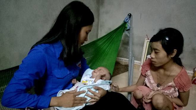 Em bé nặng 1,2 kg trong vòng tay Phó bí thư thị Đoàn Ba Đồn Trần Thị Tuyết Lan, bên phải là Hoàng Thị Hiền - người mẹ nặng 25 kg. Ảnh: Đại Dương.