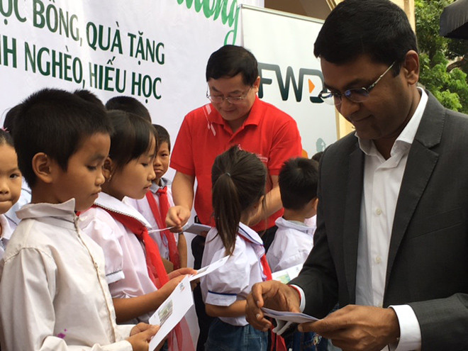 Ông Anantha (bìa phải) và ông Lê Xuân Sơn trao học bổng cho học sinh tại buổi lễ.