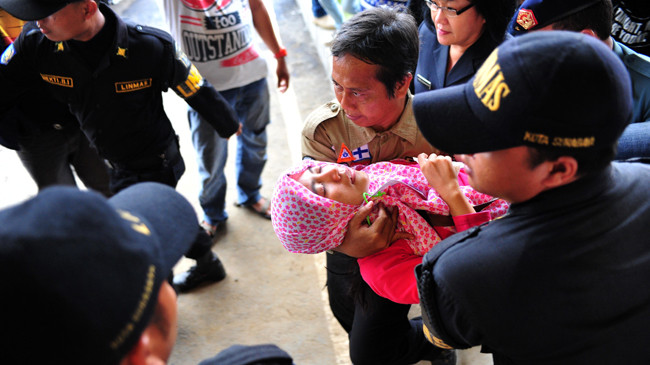  Thân nhân hành khách trên chuyến bay QZ8501 ngất khi nghe tin tìm thấy mảnh vỡ máy bay. Ảnh: Xinhua