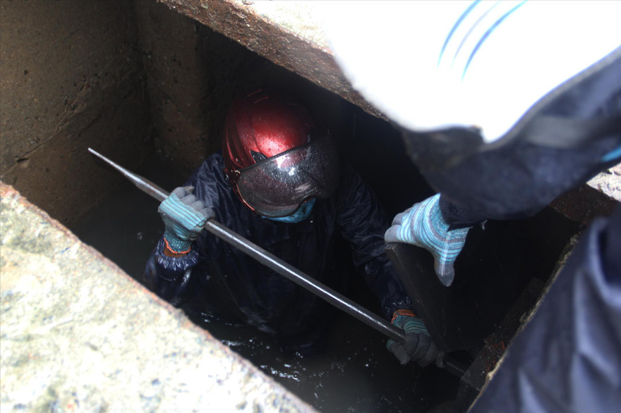 Để dọn sạch đất, rác vướng trong các ống xả, công nhân thoát nước phải ngâm mình trong nước cống liên tục. Ảnh: Giang Thanh