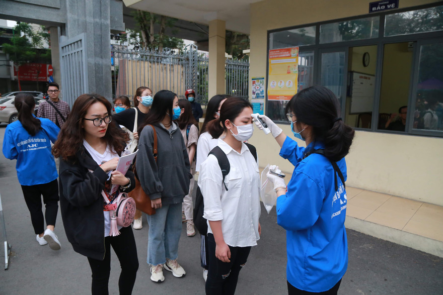 Kiểm tra thân nhiệt học sinh, sinh viên trước khi vào học. Ảnh: Như Ý