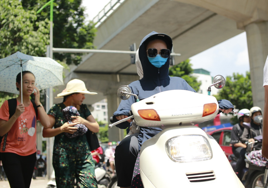 Người dân chống nắng bằng trang phục kín khi đi trên đường Xuân Thủy, Cầu Giấy, Hà Nội chiều 15/7 Ảnh: như ý