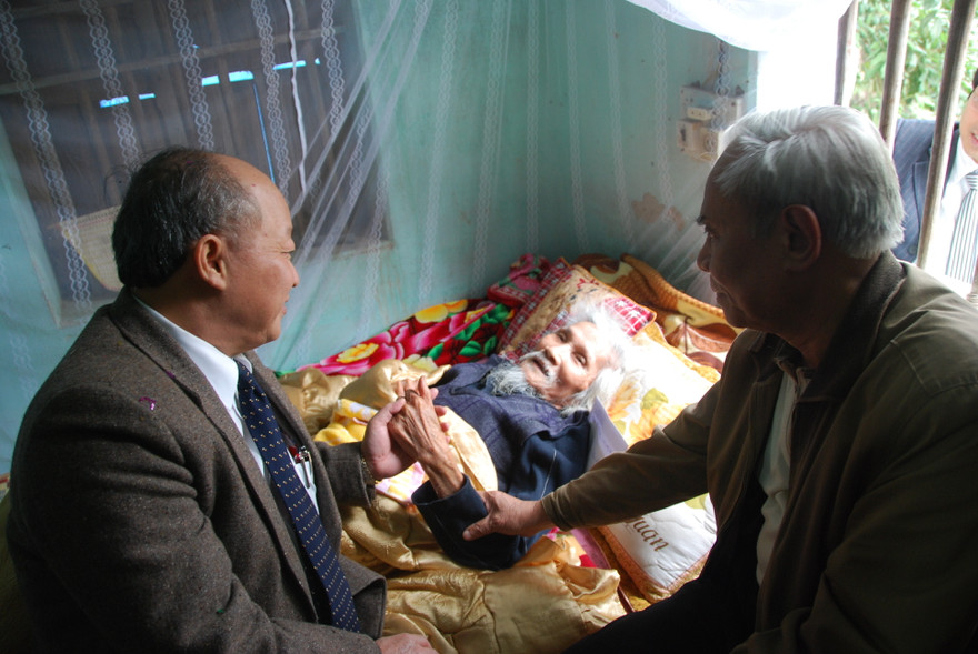 Bộ trưởng Nguyễn Quốc Triệu (trái) bên giường bệnh thi sĩ Hữu Loan